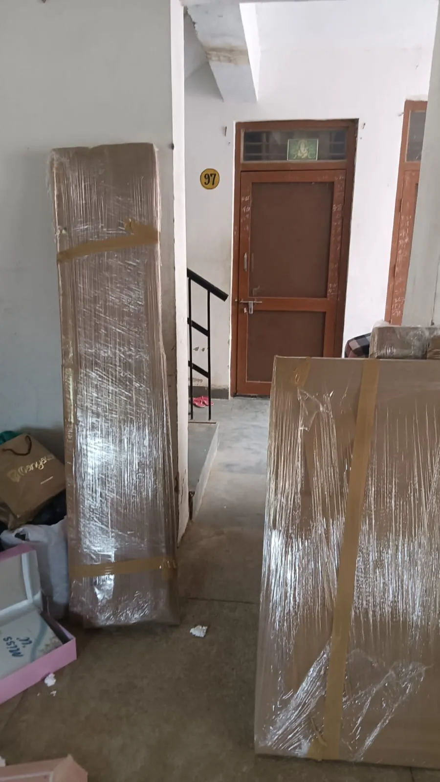 Furniture panels wrapped in protective plastic, stacked in a stairwell ready for shifting