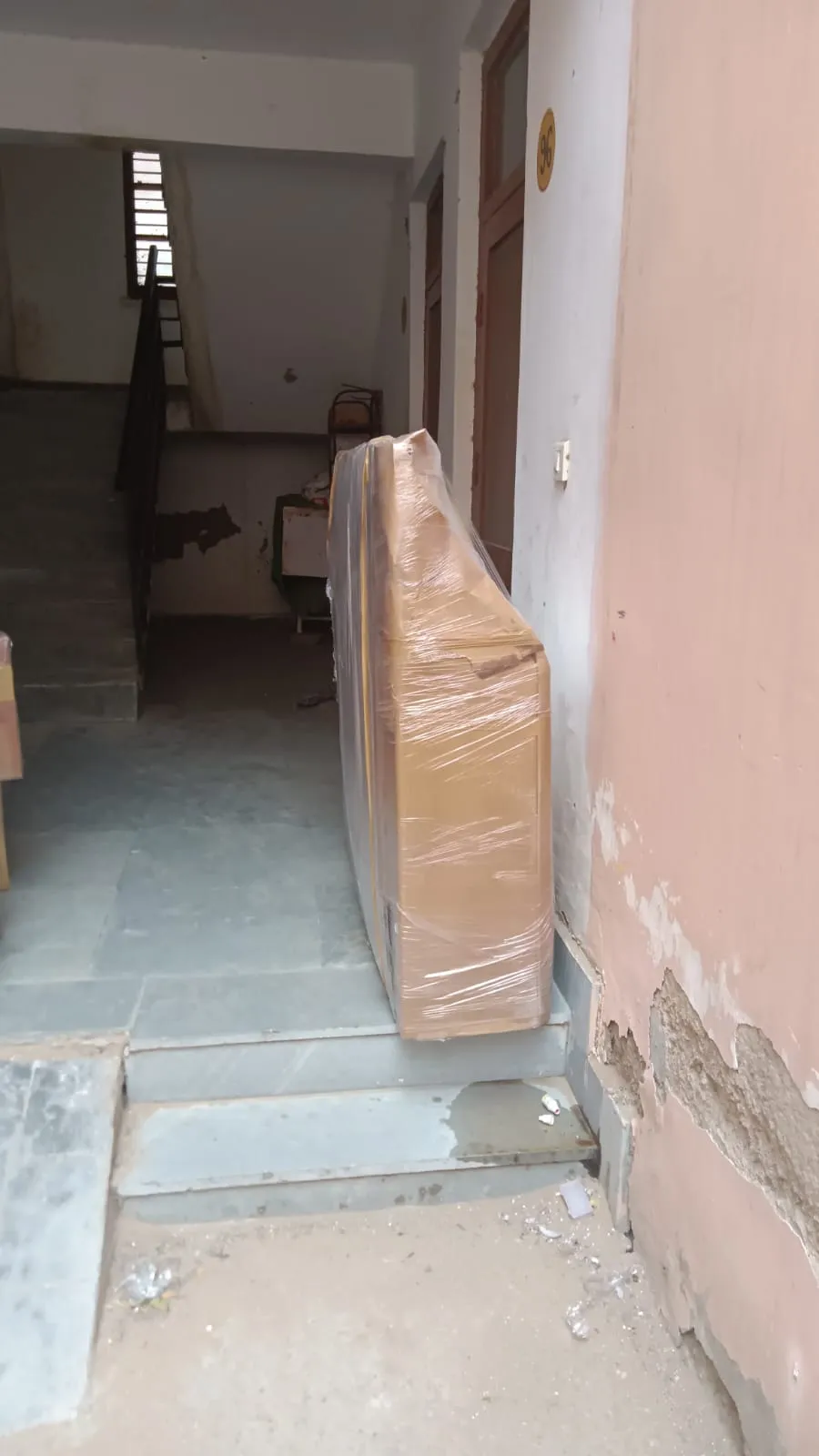 Cardboard package sealed in plastic wrap, placed by the door for pickup